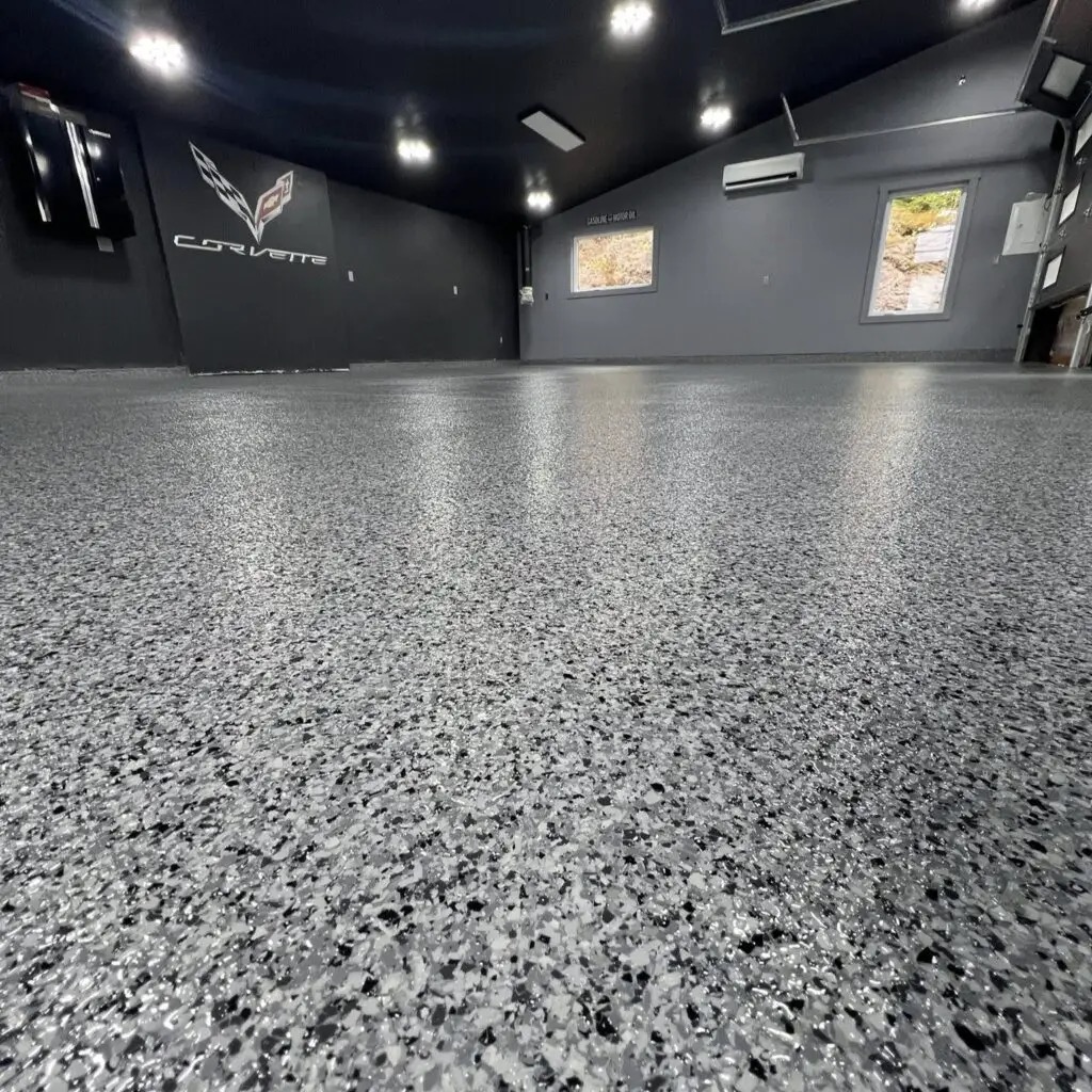 Finished residential garage with a gray and black flake floor coating and a Corvette wall sign